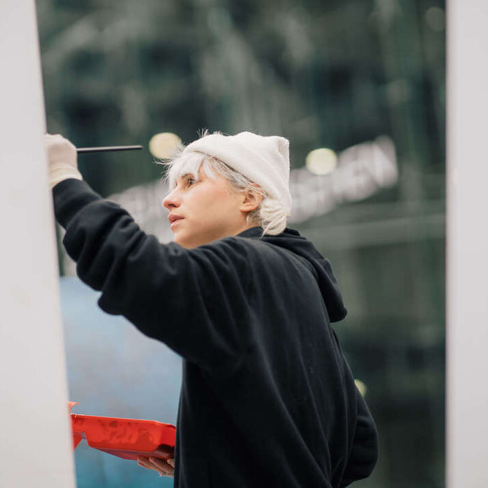 Eine Künstlerin im schwarzen Oberteil arbeitet konzentriert an ihrem Werk.